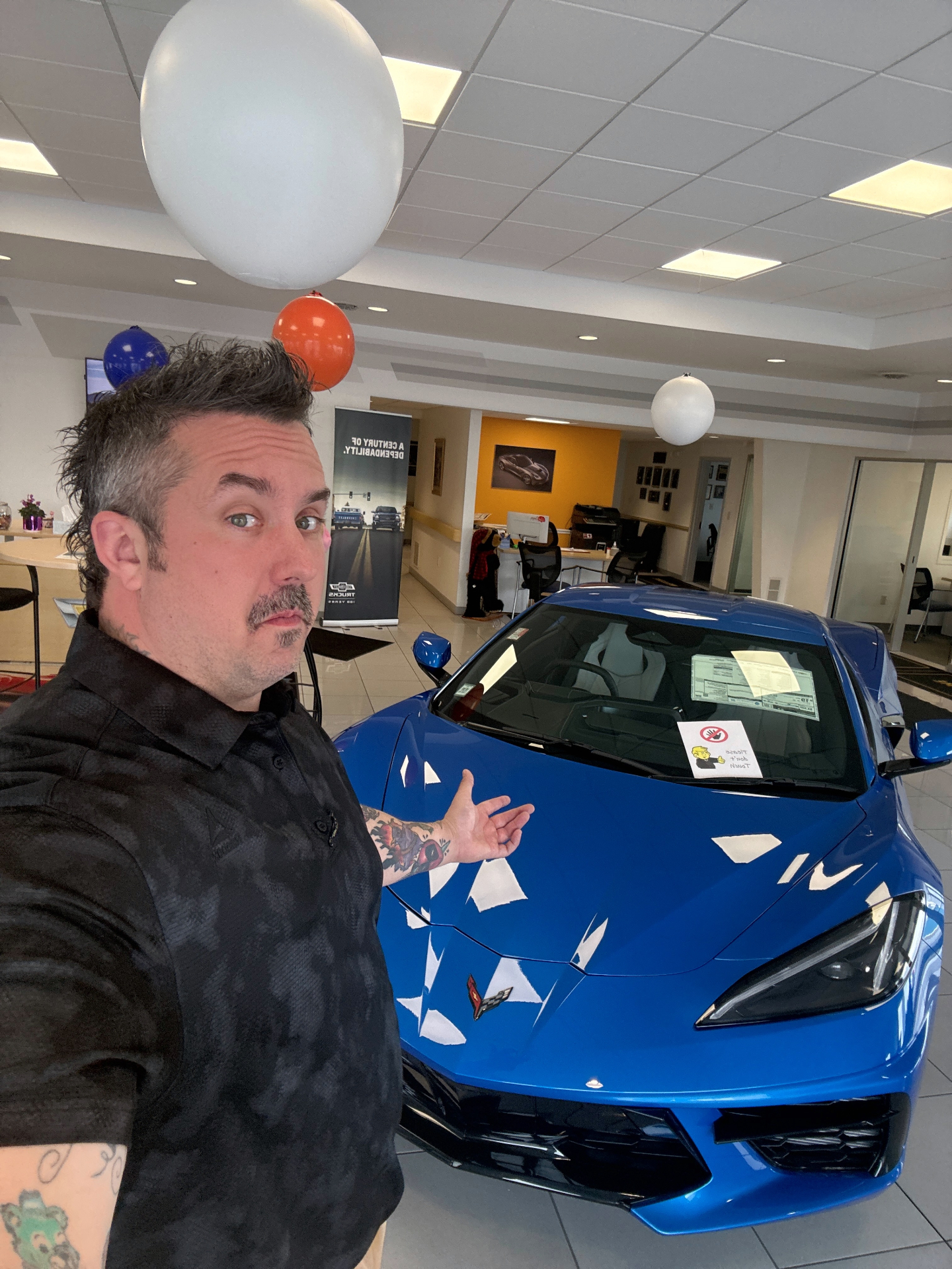 Corey Rush with a Chevrolet C8 Corvette on the showroom floor